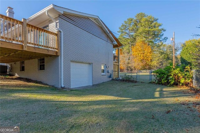 view of home's exterior with a lawn, a wooden deck, central AC unit, and a garage