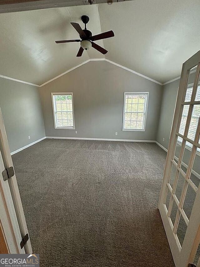 carpeted empty room featuring a healthy amount of sunlight, lofted ceiling, and crown molding