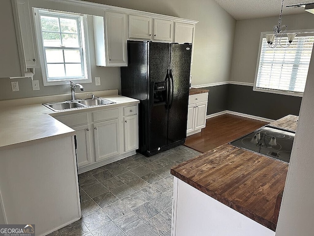 kitchen featuring decorative light fixtures, white cabinetry, black appliances, and sink