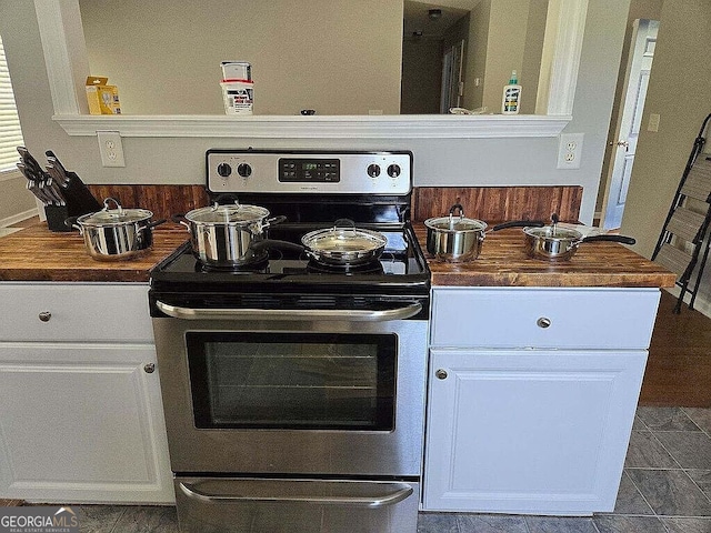 kitchen featuring white cabinetry, stainless steel range with electric stovetop, and butcher block counters