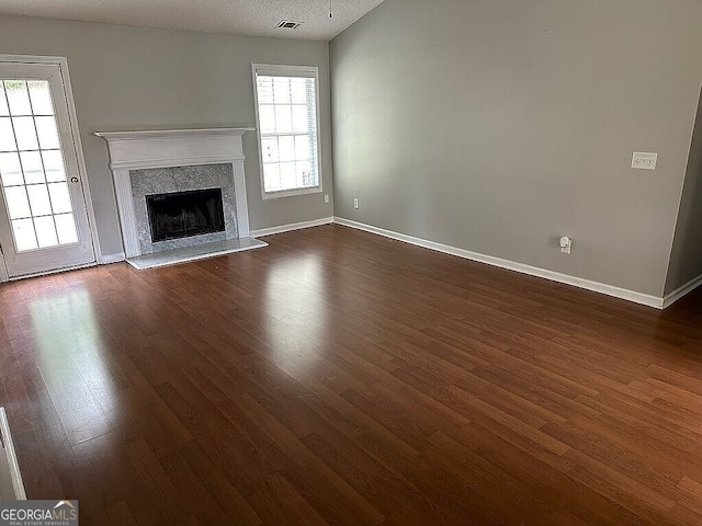 unfurnished living room with dark hardwood / wood-style flooring, a textured ceiling, and a high end fireplace