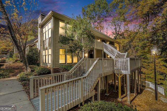 back house at dusk with a wooden deck