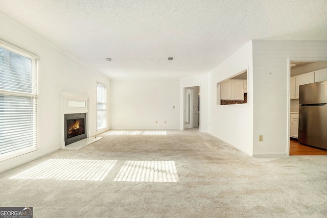 unfurnished living room featuring light carpet and a textured ceiling