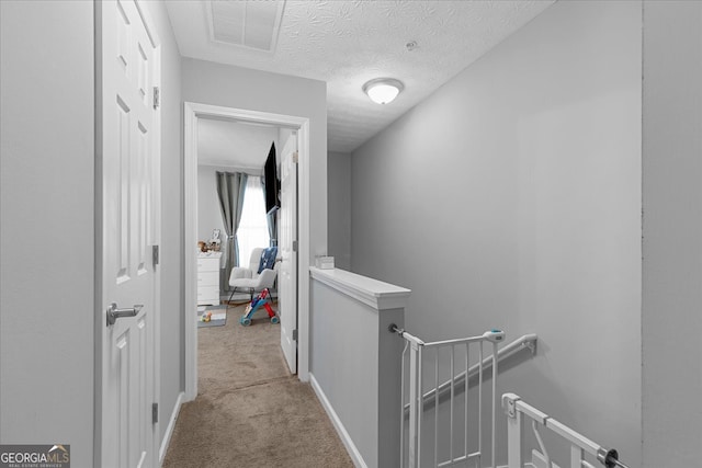 corridor featuring light colored carpet and a textured ceiling