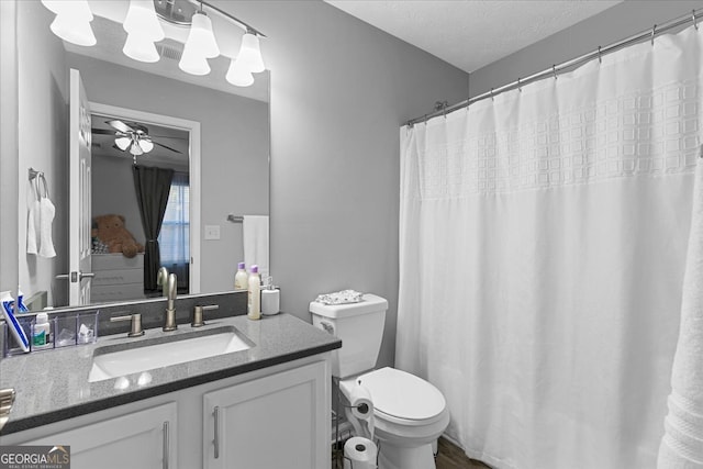 bathroom with ceiling fan, toilet, a textured ceiling, and vanity