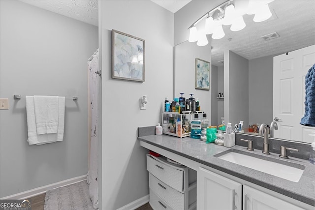 bathroom with wood-type flooring, vanity, and a textured ceiling