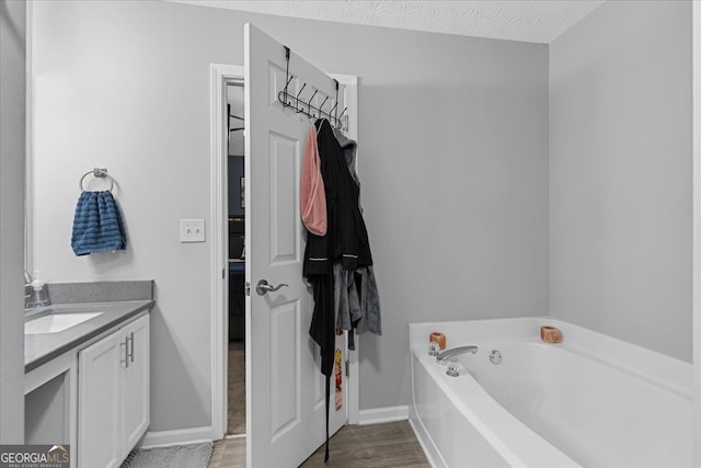 bathroom featuring hardwood / wood-style floors, vanity, a bathtub, and a textured ceiling