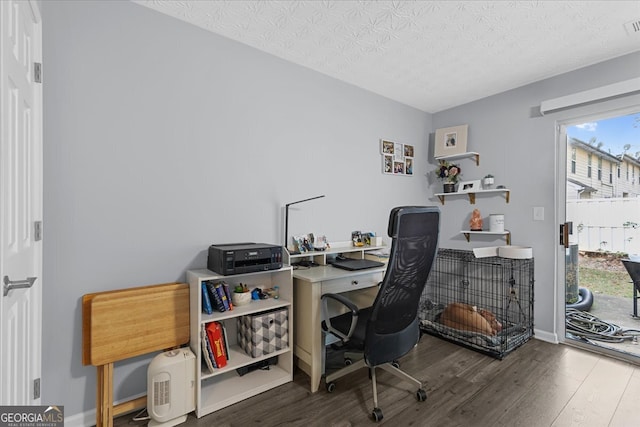 home office with a textured ceiling and dark hardwood / wood-style floors