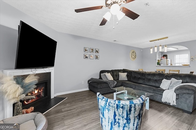 living room with hardwood / wood-style flooring, ceiling fan, and a textured ceiling