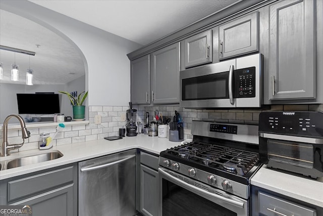 kitchen featuring gray cabinets, decorative backsplash, sink, and appliances with stainless steel finishes