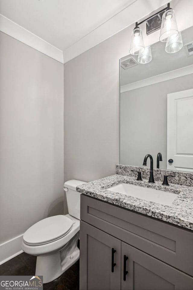 bathroom featuring vanity, ornamental molding, and toilet