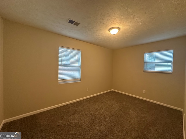 carpeted empty room with a textured ceiling