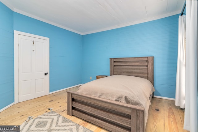 bedroom with light wood-type flooring and crown molding