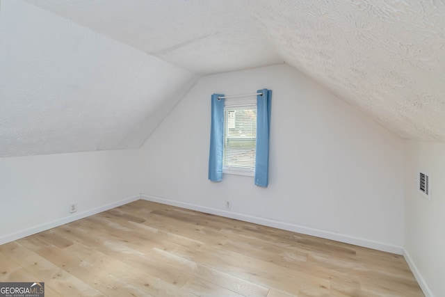 bonus room featuring a textured ceiling, light hardwood / wood-style floors, and lofted ceiling