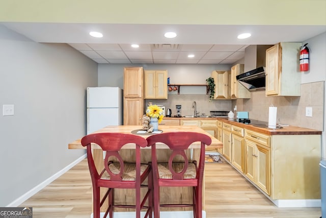 kitchen featuring light wood-type flooring, light brown cabinetry, white refrigerator, and a drop ceiling