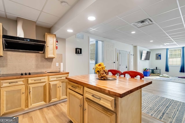 kitchen with light hardwood / wood-style floors, a kitchen island, range hood, and wooden counters