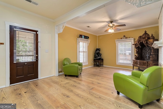 sitting room with a fireplace, light hardwood / wood-style floors, ceiling fan, and crown molding