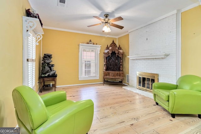 living room with a fireplace, crown molding, light hardwood / wood-style flooring, and ceiling fan