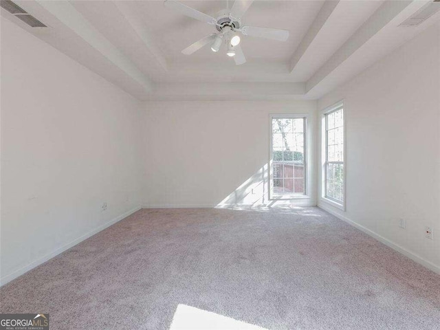 carpeted spare room featuring a raised ceiling and ceiling fan