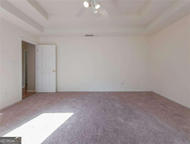 carpeted spare room featuring ceiling fan and a raised ceiling