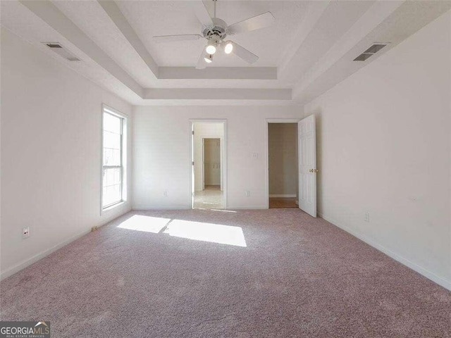 unfurnished bedroom featuring carpet flooring, a raised ceiling, and ceiling fan