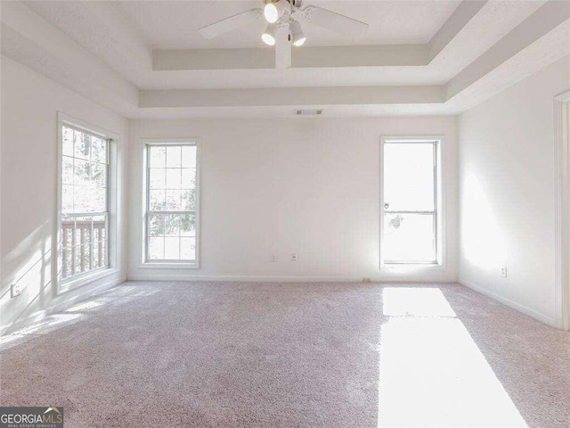 carpeted empty room featuring a raised ceiling and ceiling fan