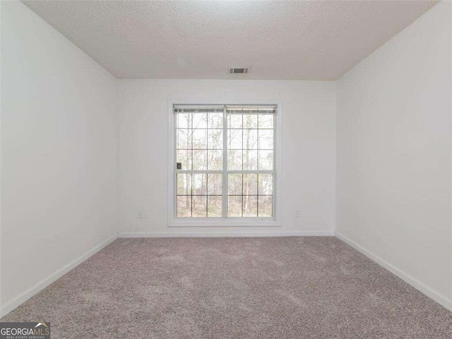 carpeted empty room with a textured ceiling