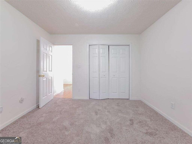 unfurnished bedroom with light colored carpet, a textured ceiling, and a closet