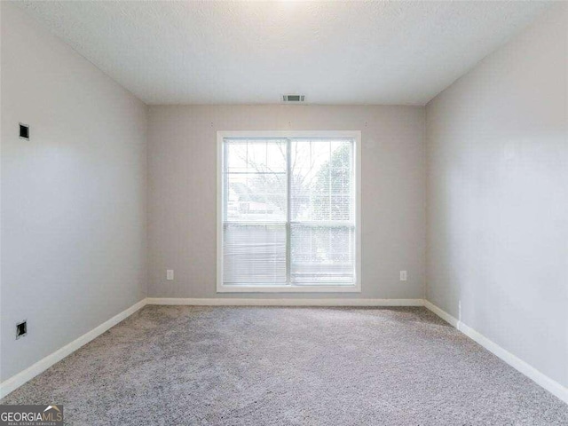 carpeted spare room with a textured ceiling