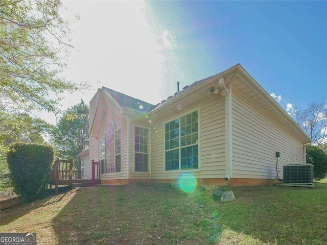 view of side of property with a yard, a deck, and cooling unit