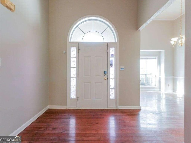 entryway with wood-type flooring, a notable chandelier, and a high ceiling