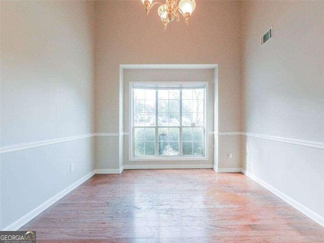 empty room with a chandelier and light hardwood / wood-style floors