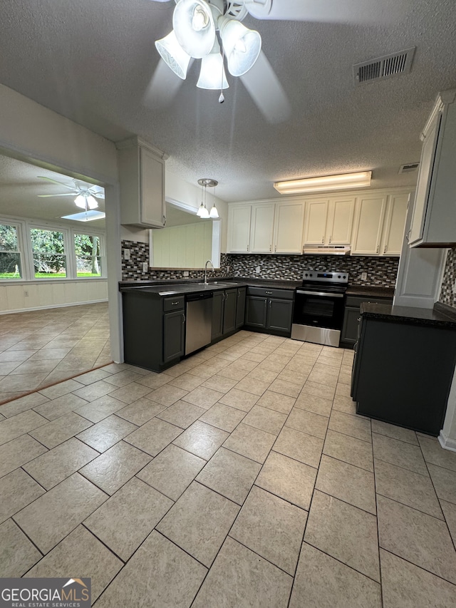 kitchen with appliances with stainless steel finishes, tasteful backsplash, gray cabinetry, a textured ceiling, and ceiling fan