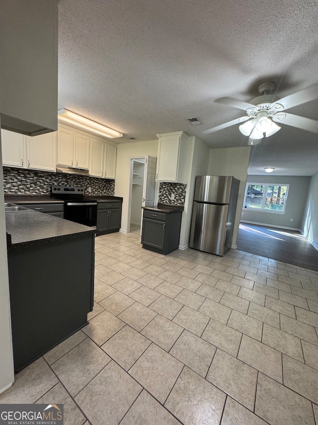 kitchen with white cabinets, decorative backsplash, ceiling fan, a textured ceiling, and appliances with stainless steel finishes