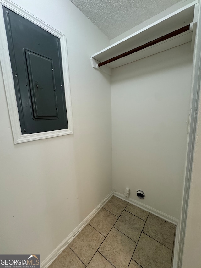 laundry room featuring tile patterned flooring, a textured ceiling, and electric panel