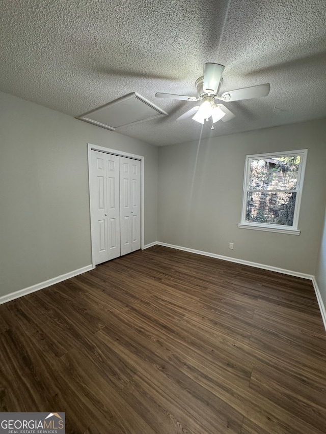 unfurnished bedroom featuring a closet, a textured ceiling, dark hardwood / wood-style floors, and ceiling fan