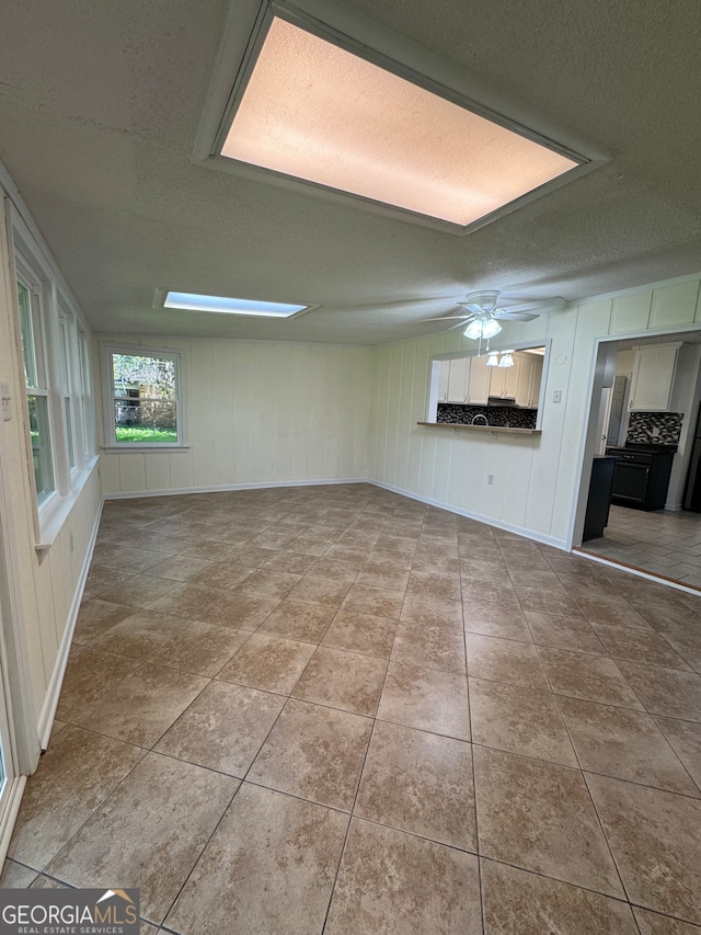 unfurnished living room featuring tile patterned flooring, ceiling fan, and a textured ceiling