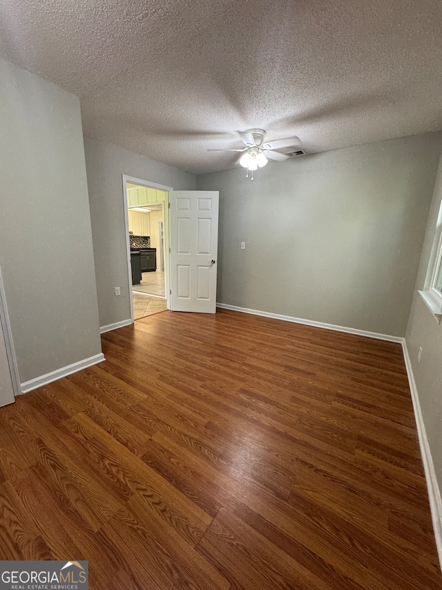 spare room featuring ceiling fan, wood-type flooring, and a textured ceiling