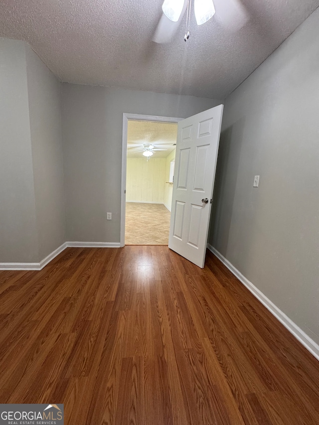 spare room featuring ceiling fan, wood-type flooring, and a textured ceiling