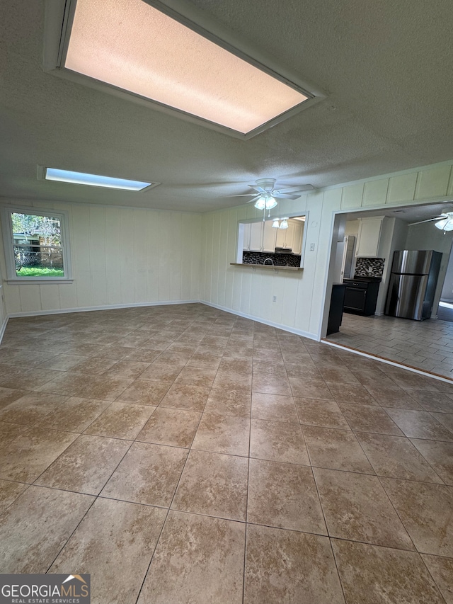 unfurnished living room featuring ceiling fan and a textured ceiling