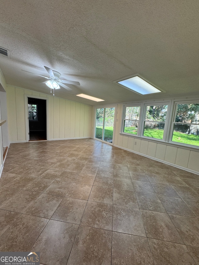 empty room featuring ceiling fan, light tile patterned floors, and a textured ceiling