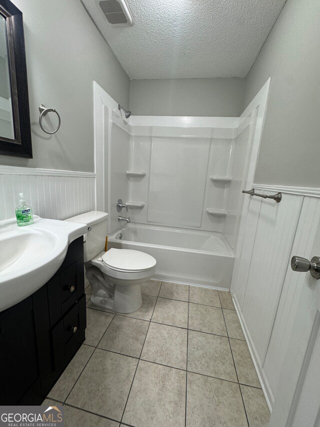 full bathroom with tile patterned flooring, a textured ceiling, toilet, and shower / bathtub combination