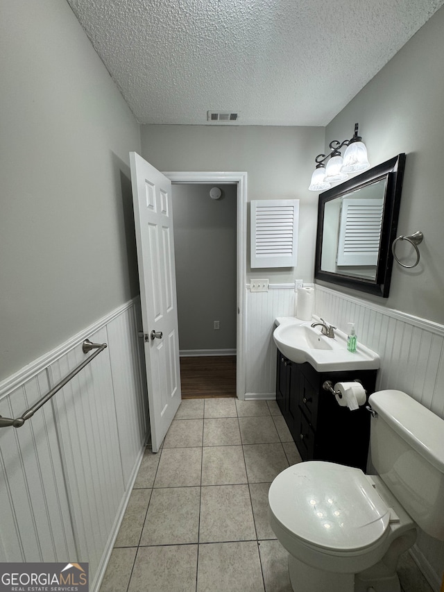 bathroom with vanity, a textured ceiling, tile patterned floors, and toilet