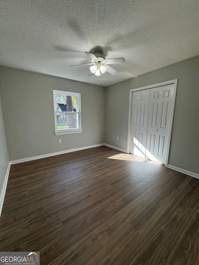 unfurnished bedroom featuring a closet, a textured ceiling, dark hardwood / wood-style floors, and ceiling fan