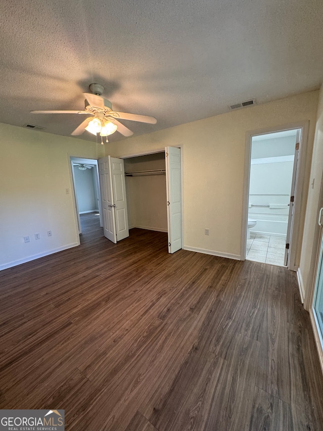 unfurnished bedroom featuring ceiling fan, dark hardwood / wood-style flooring, a textured ceiling, and ensuite bath