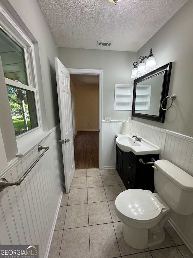 bathroom with tile patterned floors, vanity, toilet, and a textured ceiling