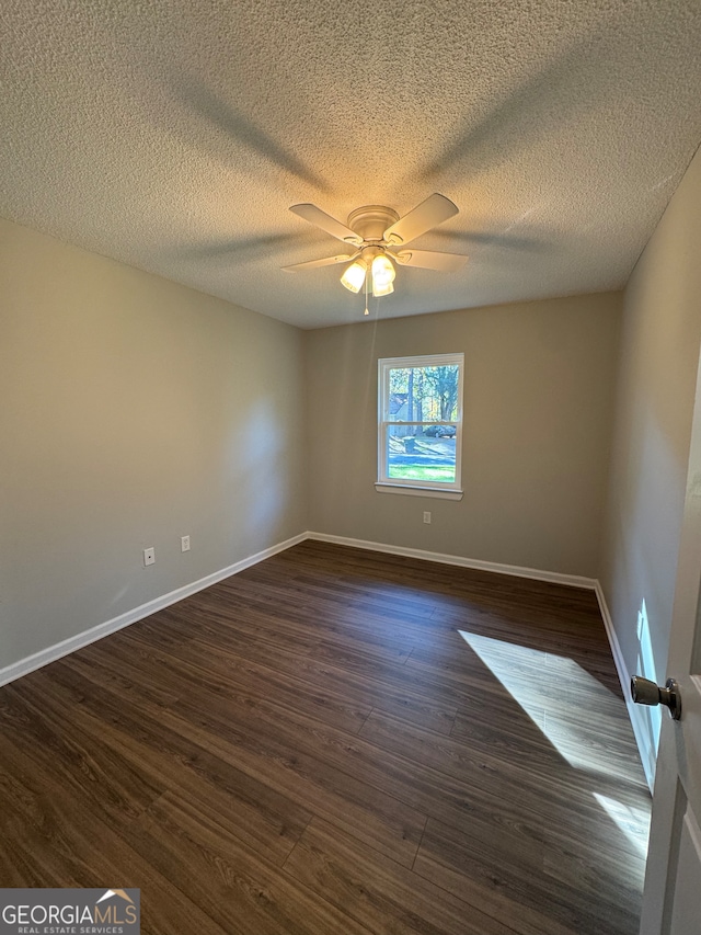 spare room with ceiling fan, dark wood-type flooring, and a textured ceiling