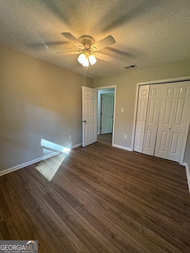 unfurnished bedroom featuring a closet, ceiling fan, dark hardwood / wood-style flooring, and a textured ceiling