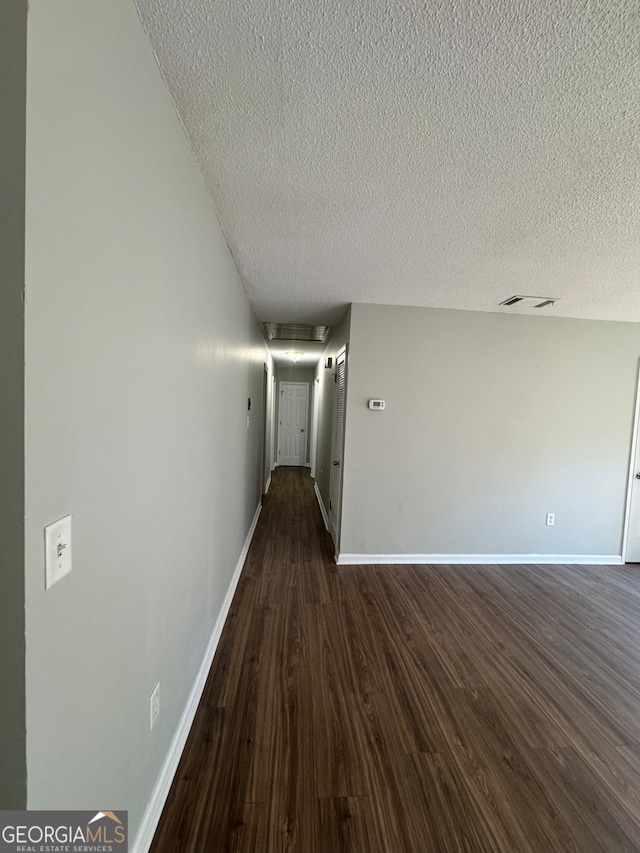 hallway featuring a textured ceiling and dark hardwood / wood-style flooring