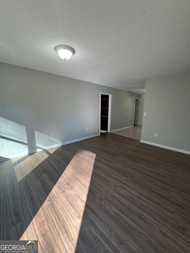 spare room featuring dark hardwood / wood-style flooring and a textured ceiling